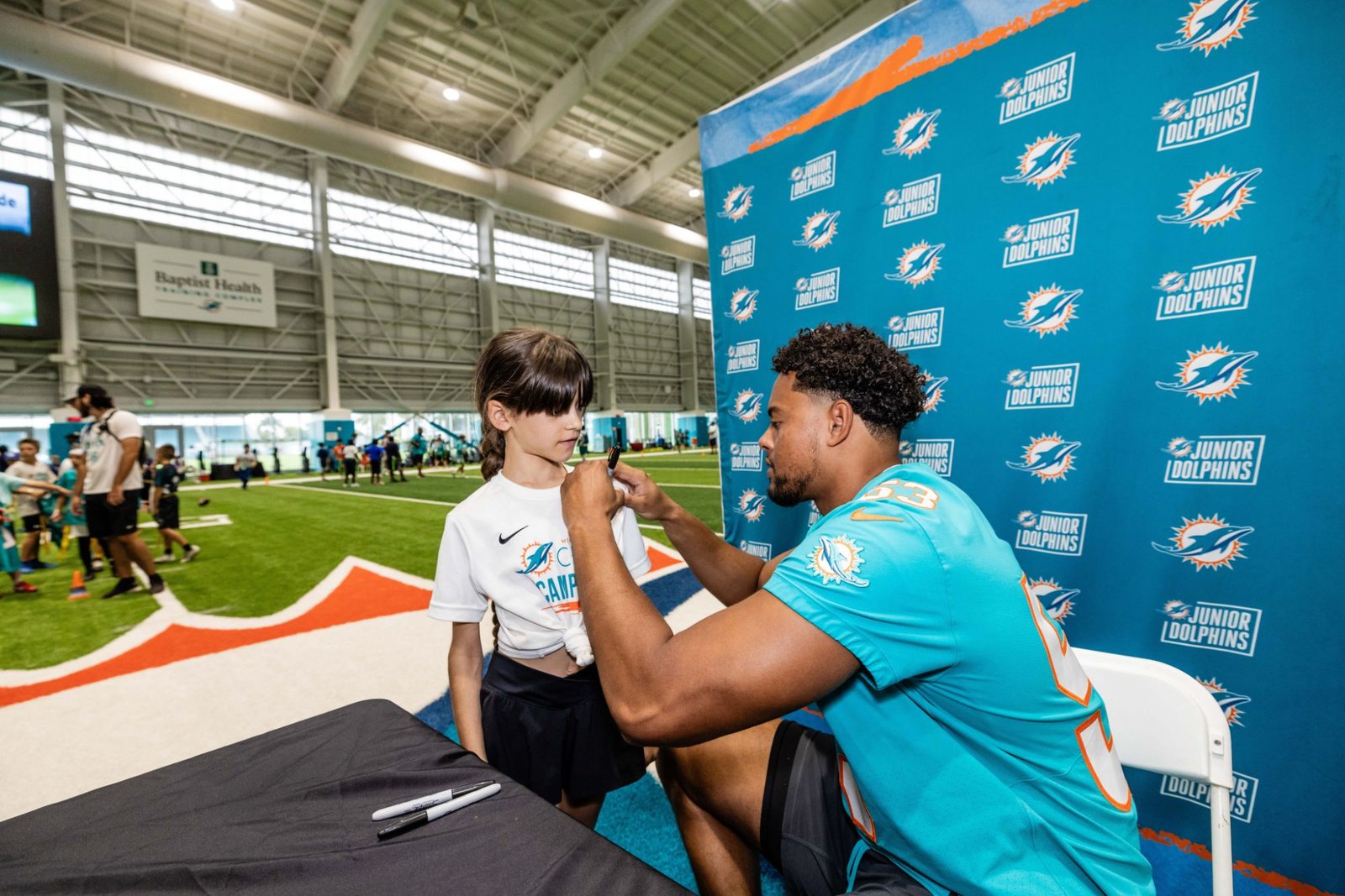 Jugador de los Miami Dolphins firmando autógrafo a jugadora de Junior Fins